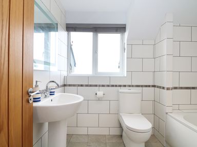 A bathroom with a pedestal sink a toilet and a bathtub with tiled walls at Myles View in Pendeen
