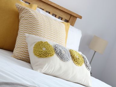 A bed with decorative pillows and a lamp in a bedroom at Myles View in Pendeen