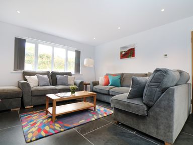 A living room with two gray sofas and a wooden coffee table on a colorful rug at Myles View in Pendeen
