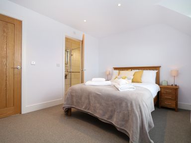 A bedroom with a wooden bed and bedside tables with lamps at Myles View in Pendeen