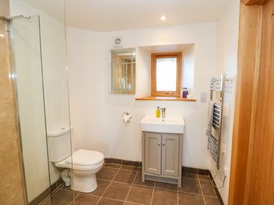 A bathroom with a toilet, sink with cabinet, towel rack, and a small window at Apple Tree Cottage in Bleatarn near Kirkby Stephen