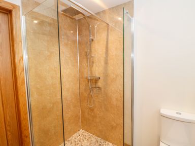 A shower area with glass doors and a tiled floor next to a toilet at Apple Tree Cottage in Bleatarn near Kirkby Stephen