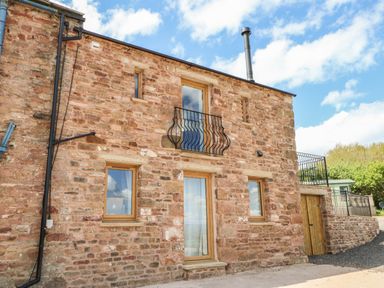 Exterior view of a stone house with wooden framed windows and metal balcony railings at Apple Tree Cottage Bleatarn near Kirkby Stephen