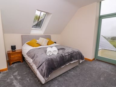 A bedroom with a double bed and side table under a skylight window at Bwthyn Eisteddfa Fach in Brynberian near Newport