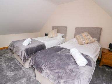 A bedroom with two single beds each with a gray blanket and a rolled white towel at Bwthyn Eisteddfa Fach in Brynberian near Newport