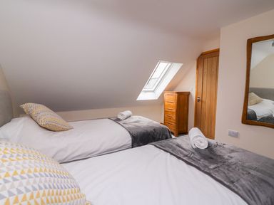 A bedroom with two single beds a wooden chest of drawers a wall mirror and a skylight window at Bwthyn Eisteddfa Fach in Brynberian near Newport