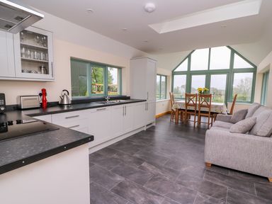 A kitchen and dining area with large windows and a gray sofa at Bwthyn Eisteddfa Fach in Brynberian near Newport