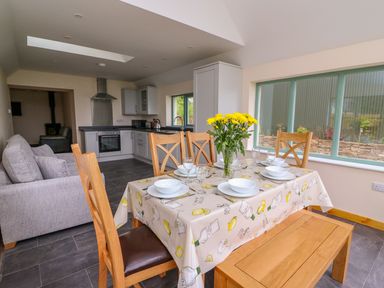 A kitchen and dining area with a table set for four and windows overlooking a garden at Bwthyn Eisteddfa Fach in Brynberian near Newport