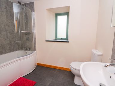 A bathroom with a bathtub shower combo toilet sink and a small window at Bwthyn Eisteddfa Fach in Brynberian near Newport