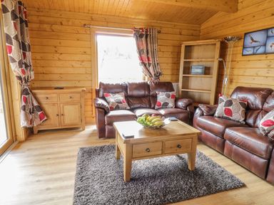 A living room with leather sofas wooden furniture and a fruit bowl on the table at Manor Farm Lodges - Red Kite Lodge in Newtown