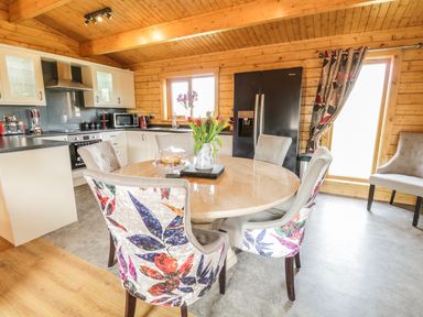 A kitchen with a round dining table and patterned chairs at Manor Farm Lodges - Red Kite Lodge in Newtown