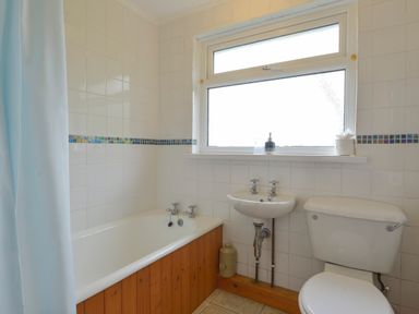 A bathroom with a bathtub a sink a toilet and a window at The Quillet in Pendeen