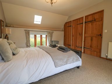 A bedroom with a bed towels on it wooden doors carpet floor and a window at Post House in Holsworthy