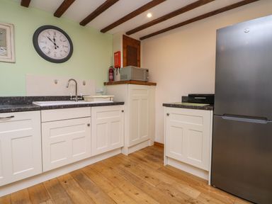 A kitchen with white cabinets a stainless steel refrigerator a microwave and a clock on the wall at The Croft in Holsworthy
