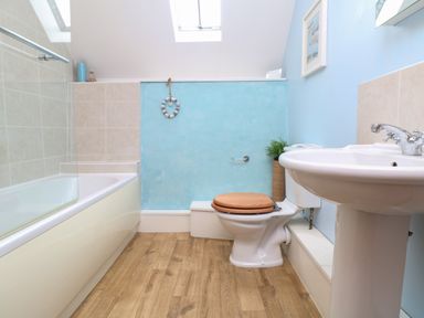 A bathroom with a bathtub a toilet with wooden seat and a sink at The Croft in Holsworthy