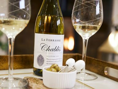 A bottle of white wine with two filled wine glasses and a small white bowl with food on a tray at Holly Edge in Moorsholm