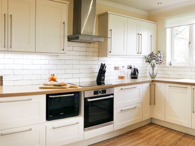 A kitchen with white cabinets wooden countertop microwave oven knife block kettle and flowers at Holly Edge in Moorsholm