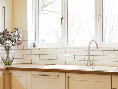A kitchen countertop with a vase of flowers next to a sink and faucet below a window at Holly Edge in Moorsholm