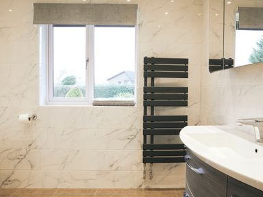 A bathroom with a window a towel radiator a wash basin and a mirror at Holly Edge in Moorsholm