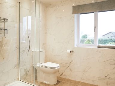A bathroom with a shower enclosure a toilet and a window with folded towels on the sill at Holly Edge in Moorsholm