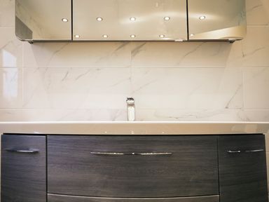 A bathroom sink with a faucet and a dark wood cabinet below a mirrored medicine cabinet at Holly Edge in Moorsholm