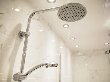 A shower area with a rain showerhead and a handheld shower in a tiled bathroom at Holly Edge in Moorsholm