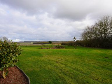 A large garden with green grass trees a birdhouse and fences at Holly Edge in Moorsholm