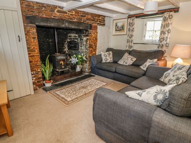 A living room with two gray sofas and a wood-burning stove in a brick fireplace at Janes Place in Lifton