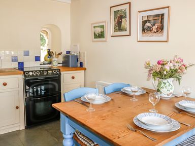 A kitchen with a wooden table set with plates and glasses and a stove with cream cabinets at Janes Place in Lifton