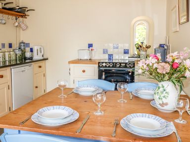 A kitchen dining table set with plates glasses and utensils and a vase of flowers at Janes Place in Lifton