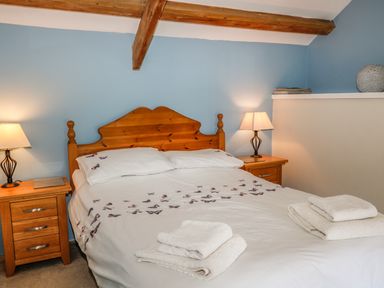 A bedroom with a wooden bed frame and bedside tables with lamps at Janes Place in Lifton