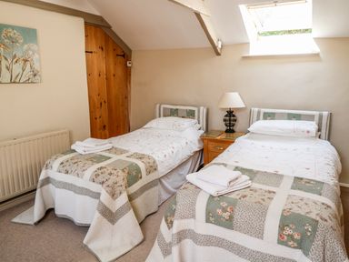 A bedroom with two single beds and a nightstand with a lamp at Jane's Place in Lifton