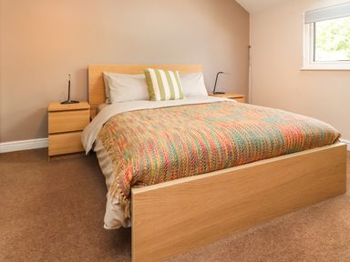 A bedroom with a wooden bed and two matching bedside tables with lamps at Palm Court in Burton-in-Kendal