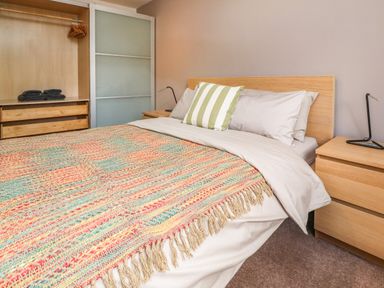 A bedroom with a bed covered with a colorful throw and white sheets at Palm Court in Burton-in-Kendal
