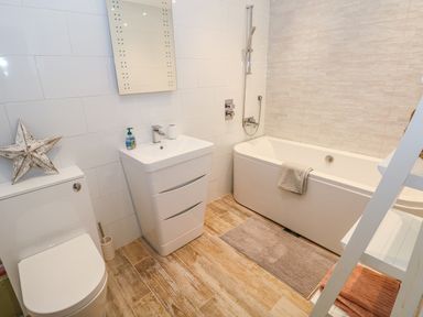 A bathroom with a toilet sink bathtub mirror and towel at Swn y mor Amroth