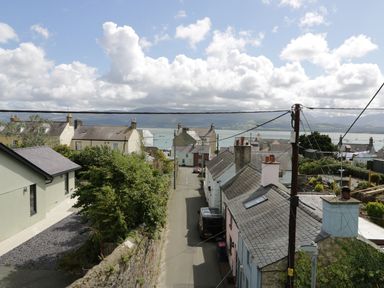 A street with houses and cars with a view of water and mountains in the background at Waverley House in Beaumaris