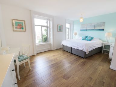 A bedroom with a double bed two bedside tables two lamps a desk a chair and two windows at Waverley House in Beaumaris