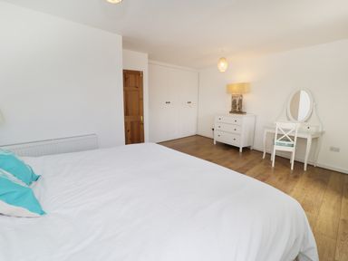 A bedroom with a bed a dresser a dressing table with a mirror and a wooden door at Waverley House in Beaumaris