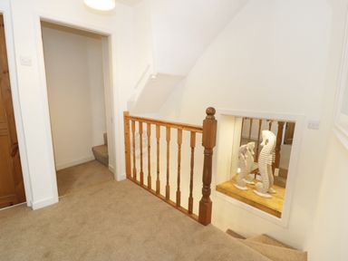A hallway with carpeted stairs wooden railing and two seahorse sculptures in a wall niche at Waverley House Beaumaris