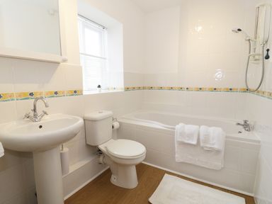 A bathroom with a sink toilet bathtub towels and a window at Waverley House in Beaumaris