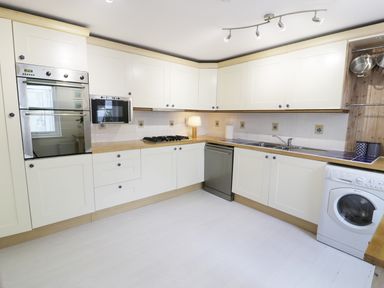 A kitchen with white cabinets built in oven microwave gas stove dishwasher sink and washing machine at Waverley House in Beaumaris