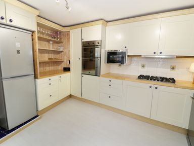 A kitchen with cream cabinets wooden countertops a refrigerator oven microwave and gas cooktop at Waverley House in Beaumaris