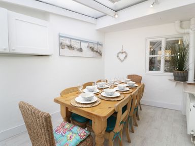 A dining room with a wooden table set for eight chairs and tableware at Waverley House in Beaumaris