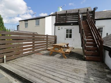 An outdoor wooden deck with a picnic table and wooden staircase leading to an upper level at Waverley House in Beaumaris
