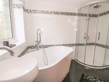 A bathroom with a bathtub sink and a glass shower enclosure at Fisher Granary in Lampeter
