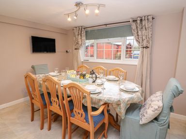 A dining room with a table set for six people and a wall-mounted TV at Fisher Granary in Lampeter