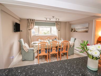 A dining room with a table set for six chairs and flower vase on a counter at Fisher Granary in Lampeter