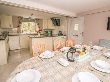 A kitchen and dining area with a table set with plates glasses and cutlery at Fisher Granary in Lampeter