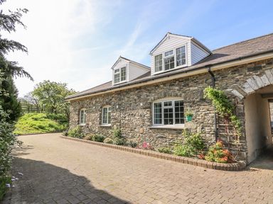 Stone exterior of a house with windows and a paved driveway at Fisher Granary in Lampeter
