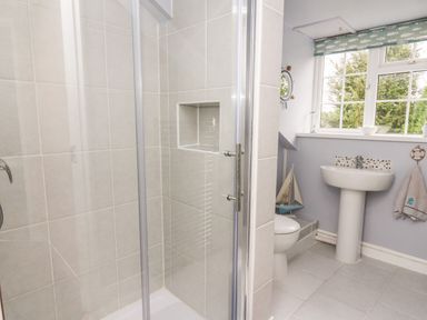 A bathroom with a shower enclosure toilet pedestal sink window and towel at Fisher Granary in Lampeter